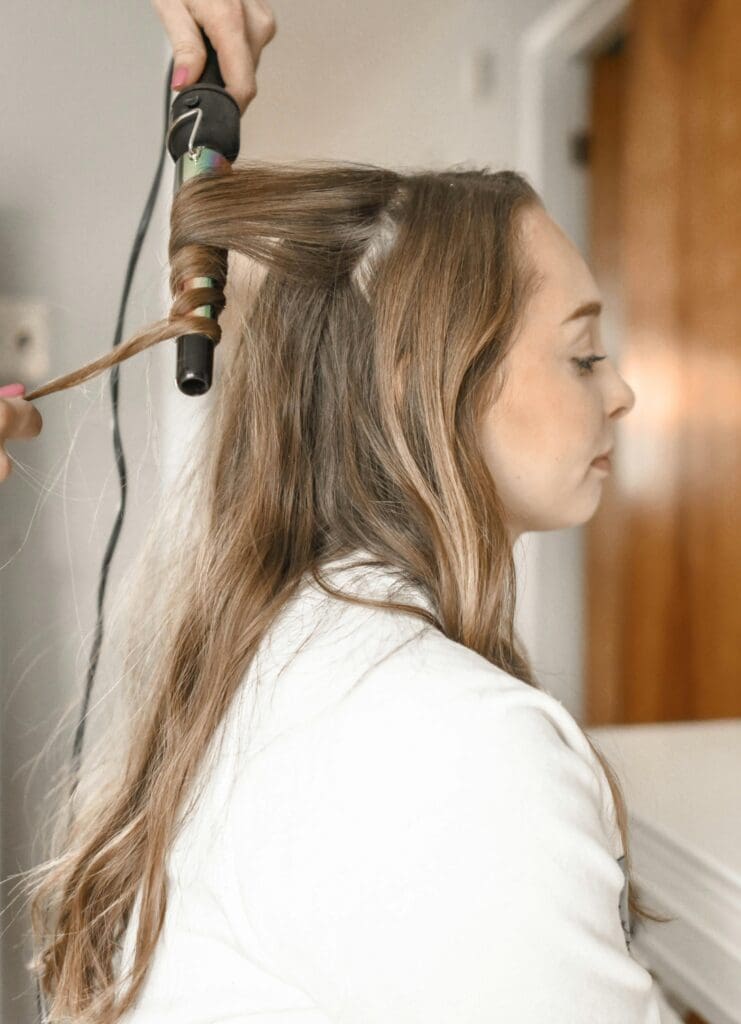 A woman blow drying her hair with a brush.