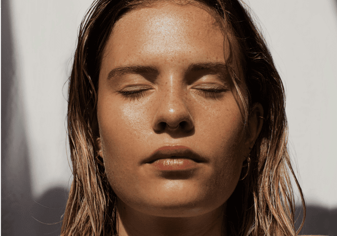 A woman with her eyes closed and her hair blowing in the wind.